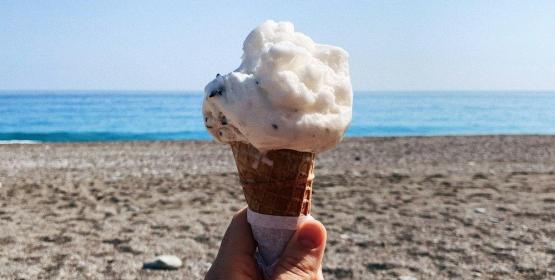 Gelato in mano, spiaggia e mare sullo sfondo.