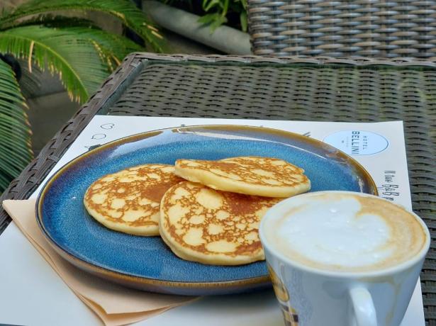 Pancake e cappuccino su un tavolo all'aperto.